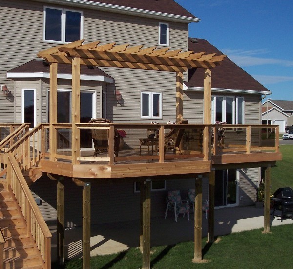 Photo of a large transitional backyard deck in Other with a pergola.
