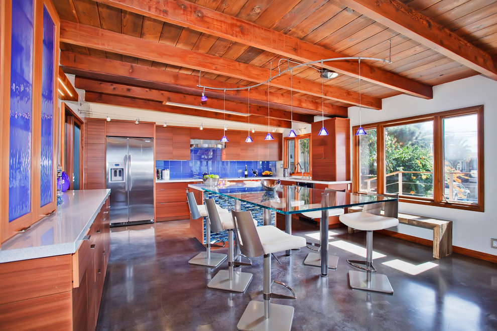 This is an example of a contemporary l-shaped eat-in kitchen in San Diego with flat-panel cabinets, medium wood cabinets, blue splashback and stainless steel appliances.