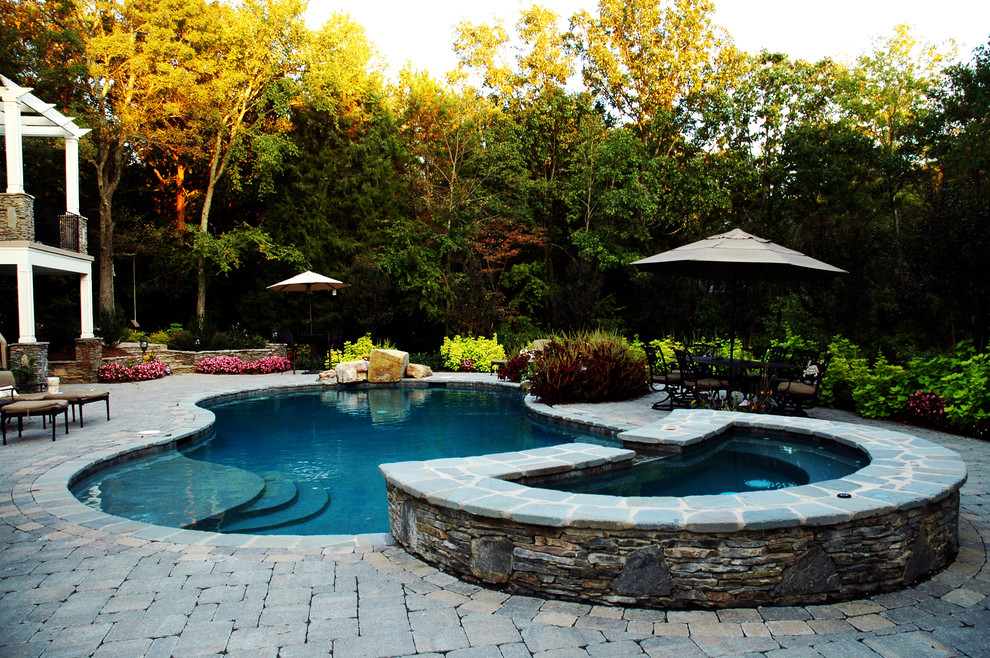 Design ideas for a traditional custom-shaped pool in Houston with natural stone pavers.