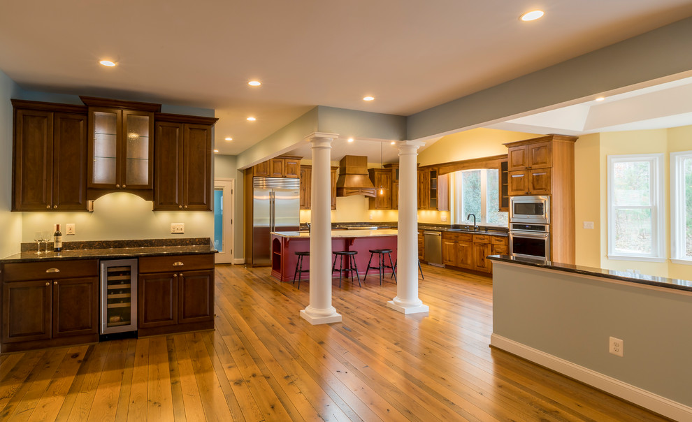 Photo of a large traditional l-shaped eat-in kitchen in DC Metro with medium hardwood floors, brown floor, an undermount sink, raised-panel cabinets, medium wood cabinets, granite benchtops, stainless steel appliances and with island.