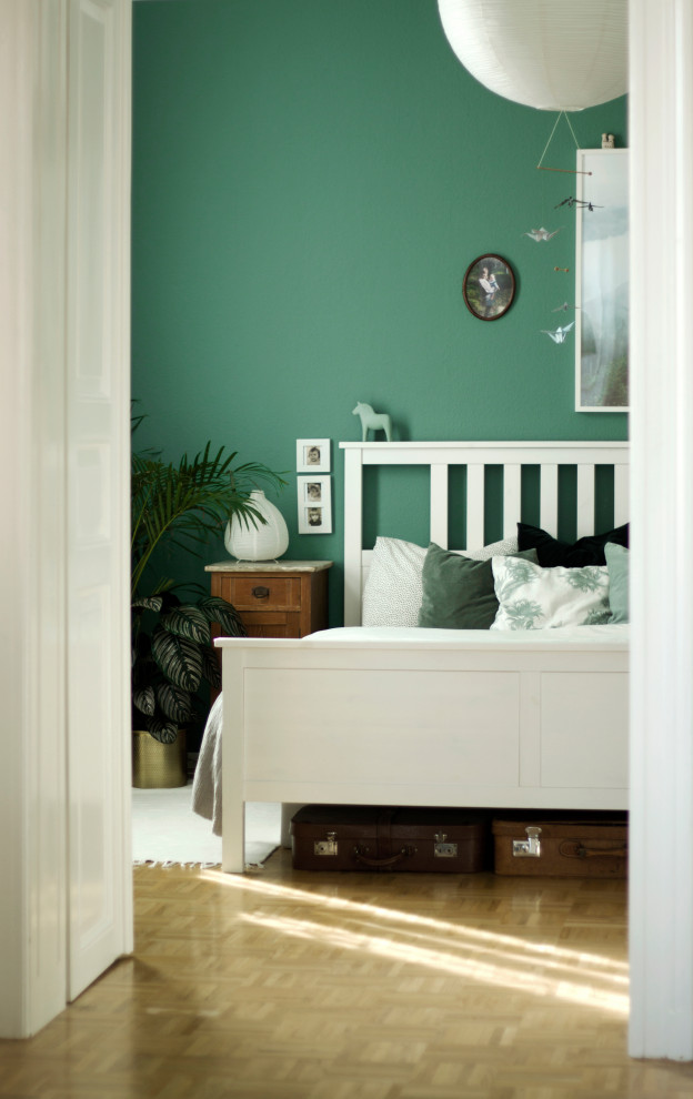 This is an example of a large scandi master bedroom in Dresden with green walls and light hardwood flooring.