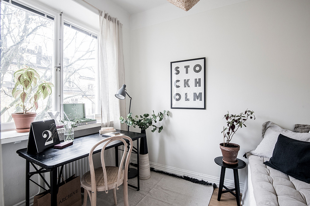 This is an example of a small scandinavian home office in Stockholm with white walls, no fireplace, a freestanding desk, dark hardwood floors and brown floor.