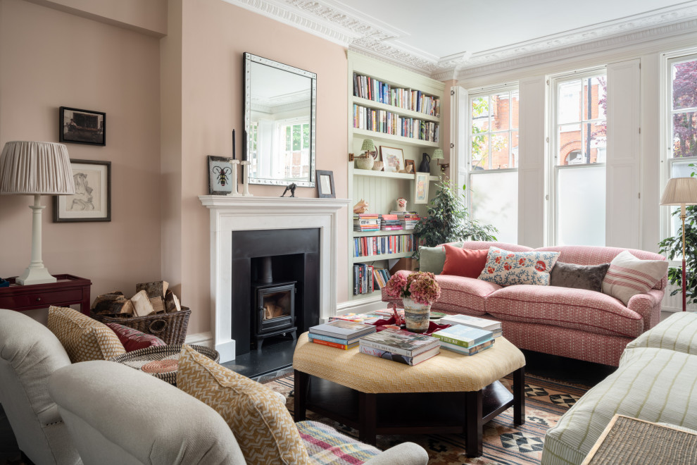 Large transitional formal enclosed living room in London with pink walls, a standard fireplace and a metal fireplace surround.