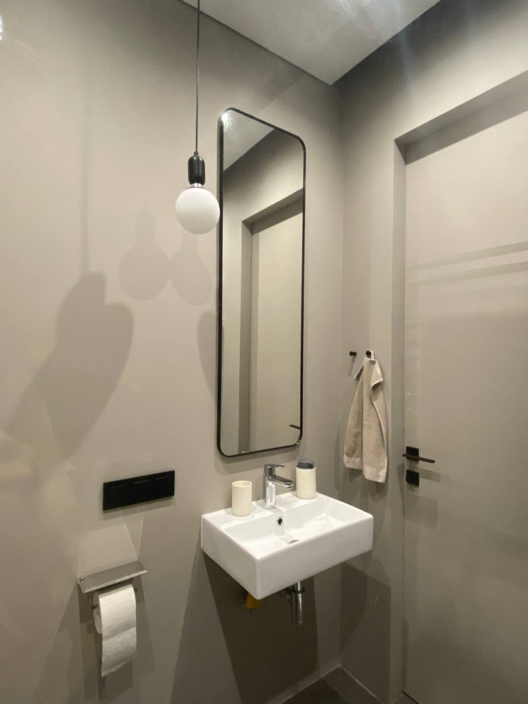 Источник вдохновения для домашнего уюта: туалет в современном стиле с бежевыми стенами, подвесной раковиной и серым полом