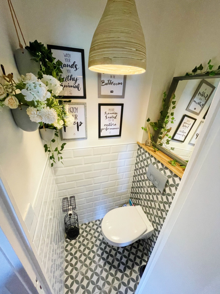 Kleine Mid-Century Gästetoilette mit Wandtoilette, weißen Fliesen, Keramikfliesen, Zementfliesen für Boden, schwarzem Boden und brauner Waschtischplatte