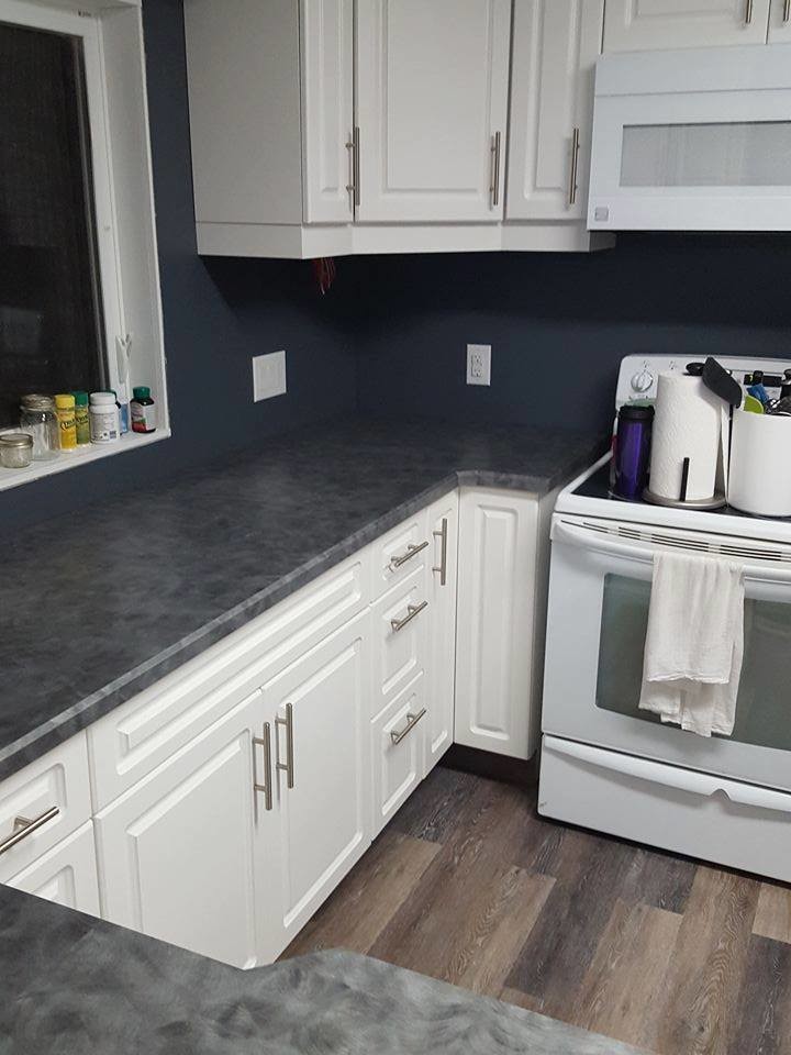 Kitchen - transitional medium tone wood floor and brown floor kitchen idea with a drop-in sink, raised-panel cabinets, white cabinets, white appliances and limestone countertops