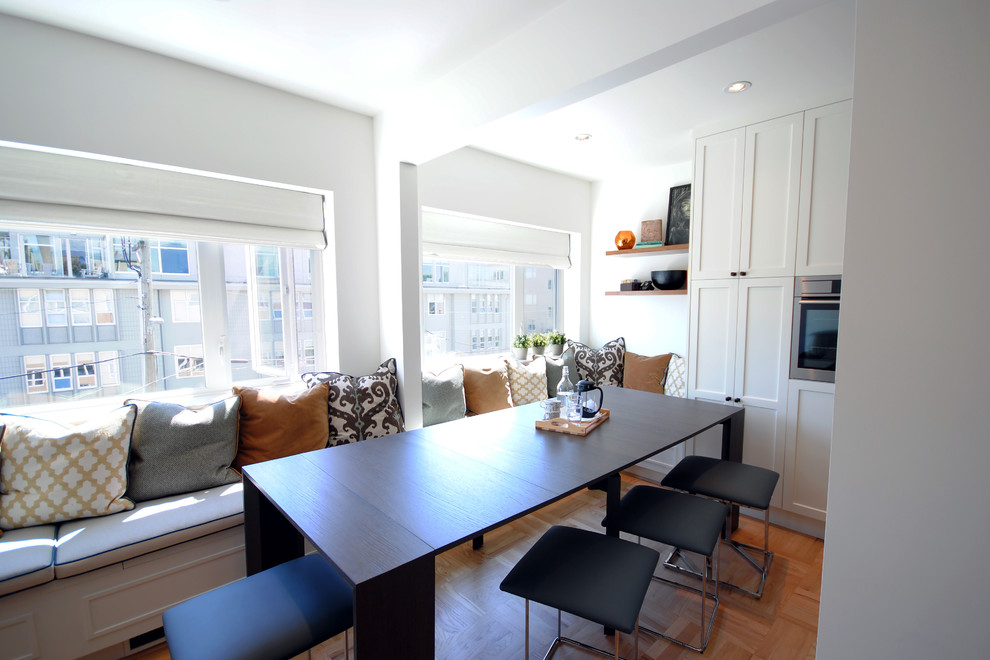Photo of a small contemporary kitchen/dining combo in Vancouver with white walls and light hardwood floors.