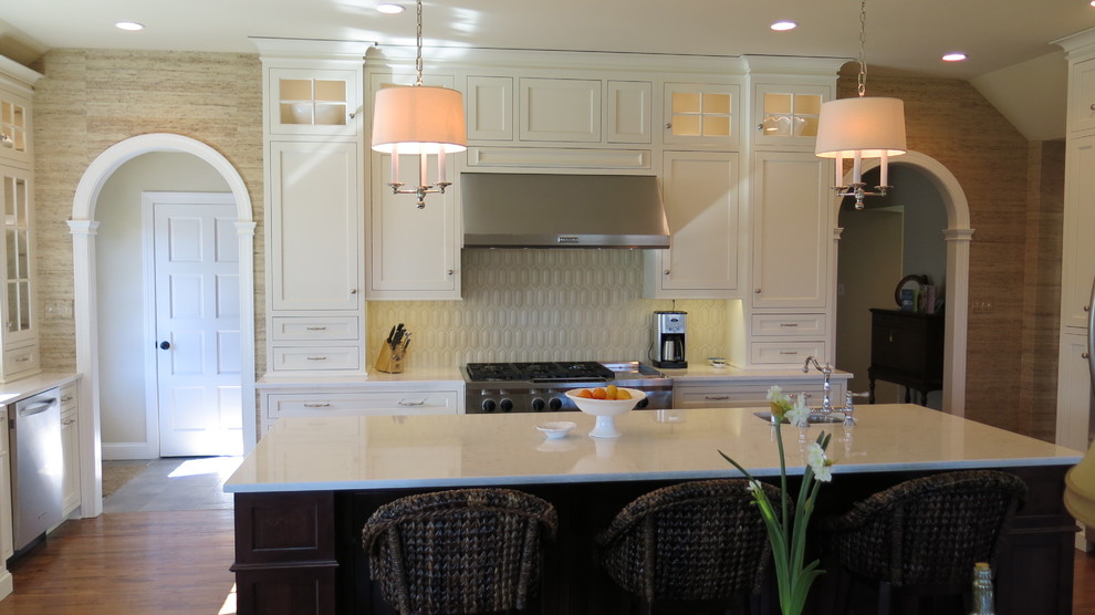 Example of a transitional kitchen design with white cabinets, quartz countertops and white backsplash