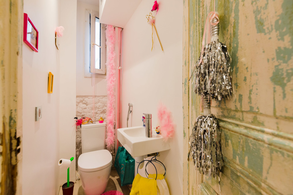 Bohemian cloakroom in Paris with a wall-mounted sink, a two-piece toilet and white walls.