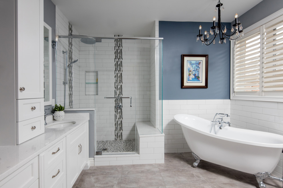 Inspiration for a large transitional master bathroom in Other with shaker cabinets, white cabinets, a corner shower, white tile, gray tile, ceramic tile, blue walls, ceramic floors, an undermount sink, engineered quartz benchtops, a hinged shower door, a claw-foot tub and grey floor.