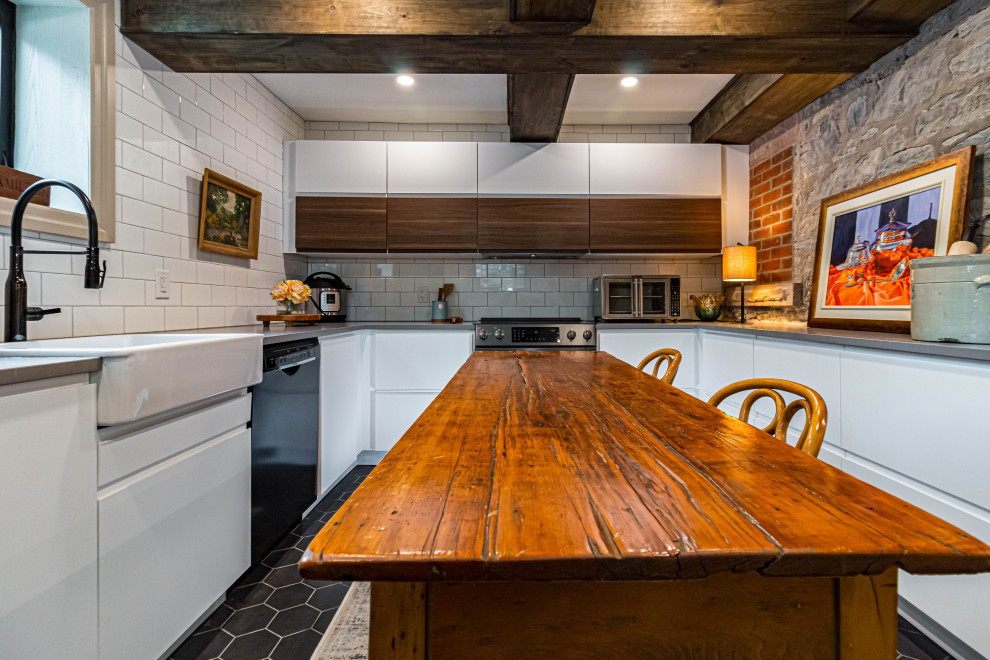 Inspiration for a mid-sized rustic u-shaped ceramic tile, black floor and exposed beam eat-in kitchen remodel in Toronto with a farmhouse sink, flat-panel cabinets, white cabinets, quartz countertops, white backsplash, subway tile backsplash, stainless steel appliances, an island and gray countertops