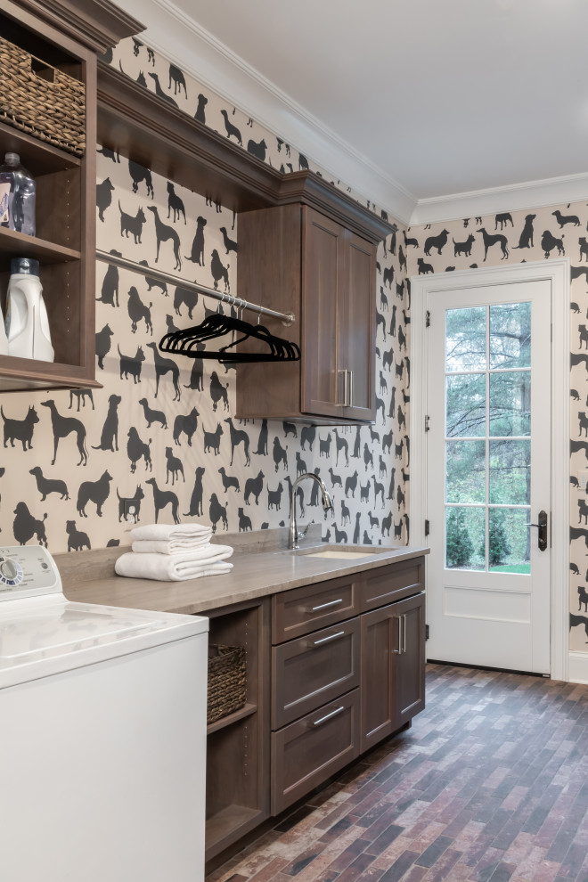 Inspiration for a large transitional galley brick floor and wallpaper utility room remodel in St Louis with an undermount sink, recessed-panel cabinets, dark wood cabinets, a side-by-side washer/dryer and beige countertops