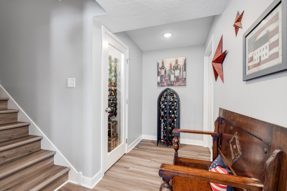 This is an example of a large transitional wine cellar in Other with vinyl floors, display racks and brown floor.
