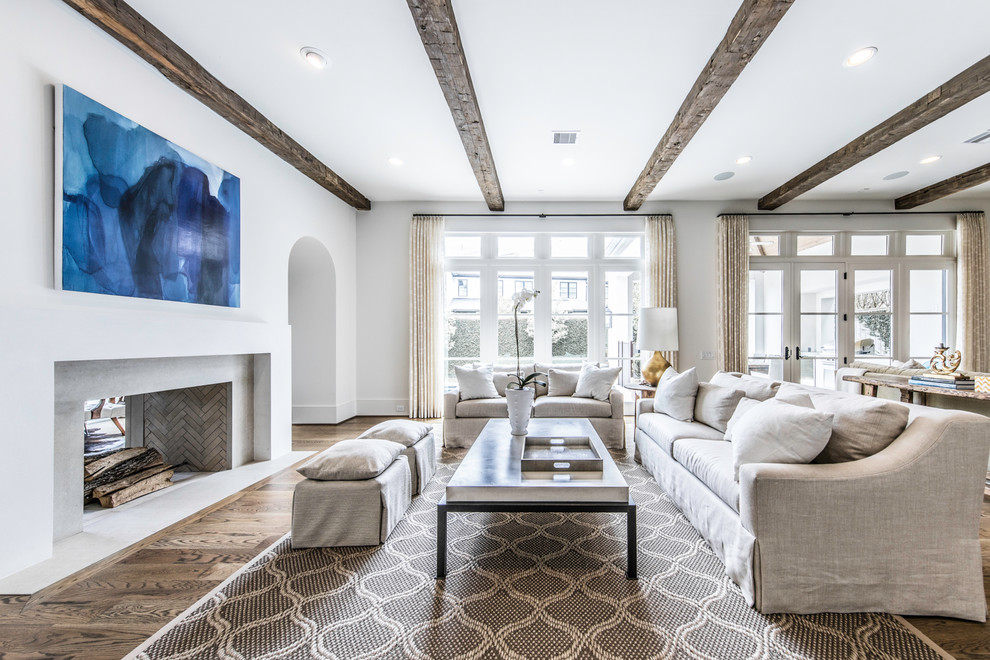 This is an example of a large mediterranean living room in Houston with white walls, dark hardwood floors, a standard fireplace, a plaster fireplace surround, no tv and white floor.