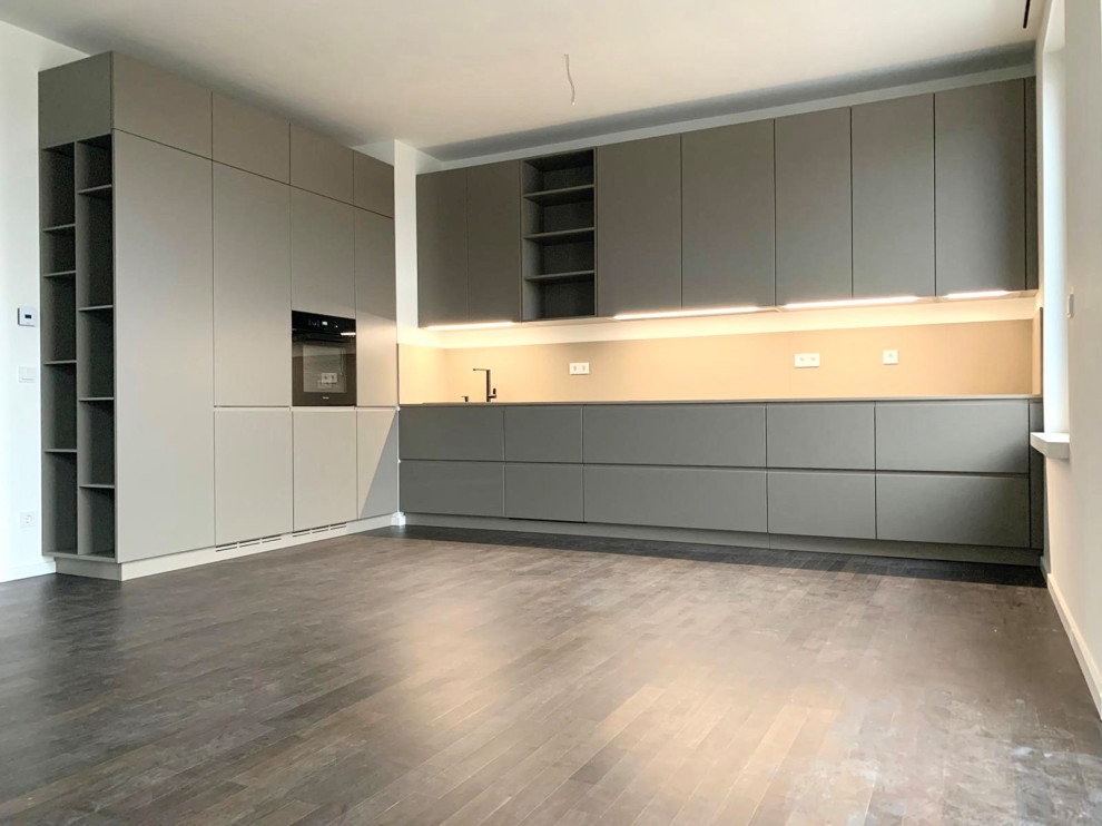 This is an example of a large contemporary l-shaped eat-in kitchen in Berlin with a drop-in sink, flat-panel cabinets, black appliances and no island.