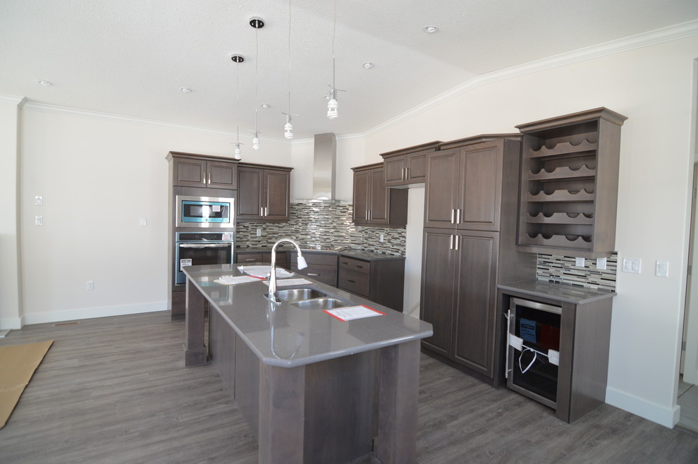 Mid-sized contemporary l-shaped eat-in kitchen in Calgary with a double-bowl sink, raised-panel cabinets, grey cabinets, quartzite benchtops, multi-coloured splashback, glass tile splashback, stainless steel appliances, linoleum floors and with island.