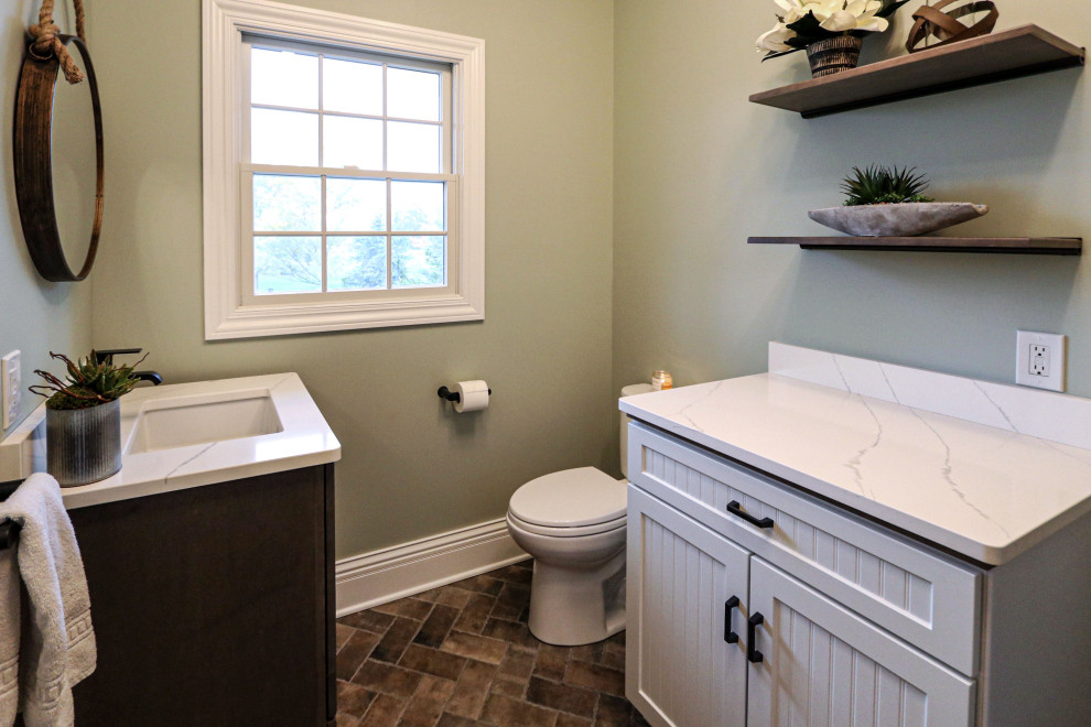 This is an example of a small classic cloakroom in Cleveland with flat-panel cabinets, medium wood cabinets, a two-piece toilet, green walls, porcelain flooring, a submerged sink, engineered stone worktops, brown floors, white worktops and a freestanding vanity unit.
