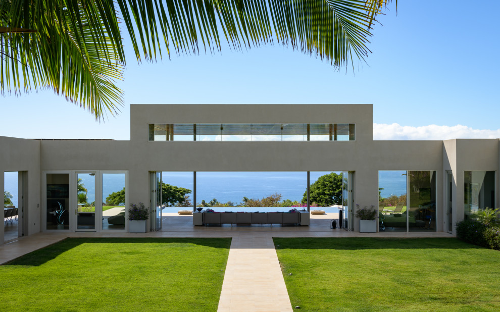 Photo of a large modern one-storey stucco white house exterior in Hawaii with a flat roof and a white roof.
