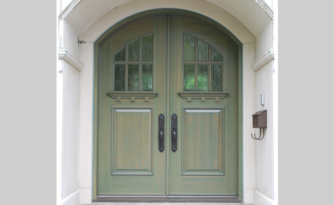 This is an example of a country front door in Montreal with a double front door, white walls and a green front door.
