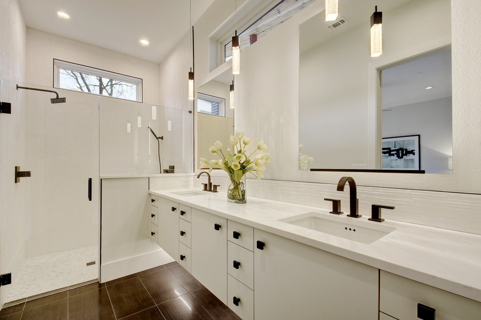 This is an example of a contemporary bathroom in Austin with flat-panel cabinets, white cabinets, a curbless shower, white tile, white walls, an undermount sink, brown floor and a hinged shower door.