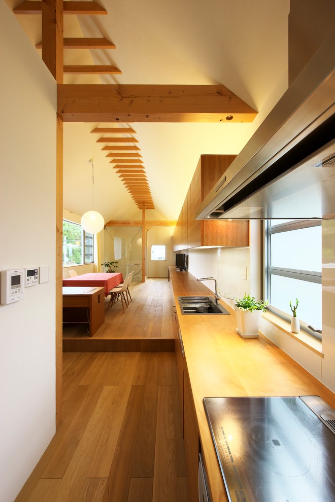 Asian single-wall open plan kitchen in Nagoya with a single-bowl sink, flat-panel cabinets, medium wood cabinets, medium hardwood floors, a peninsula and brown floor.
