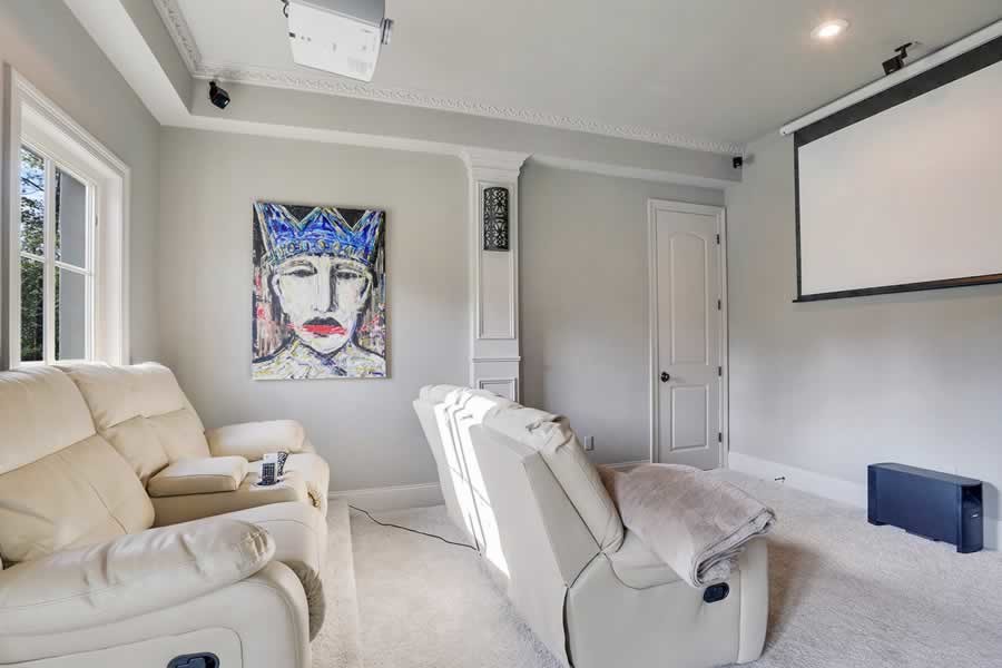 Photo of a small transitional enclosed home theatre in New Orleans with grey walls, carpet, a projector screen and grey floor.