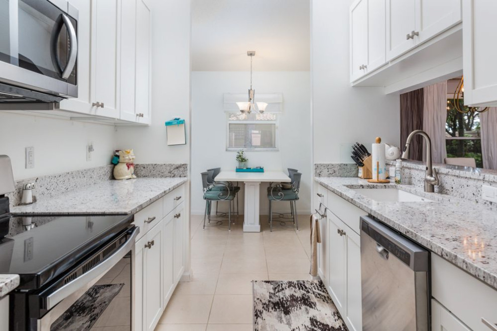 Design ideas for a small transitional galley separate kitchen in Miami with a drop-in sink, shaker cabinets, white cabinets, granite benchtops, white splashback, granite splashback, stainless steel appliances, ceramic floors, no island, beige floor and yellow benchtop.