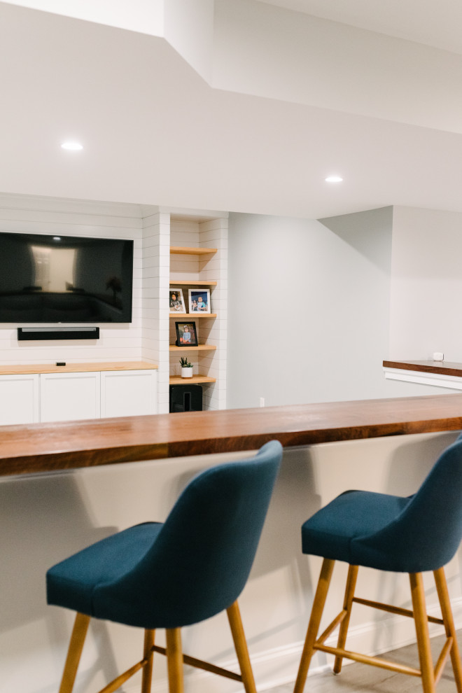 This is an example of a large modern basement in Philadelphia with a home bar, white walls, vinyl flooring, grey floors and tongue and groove walls.
