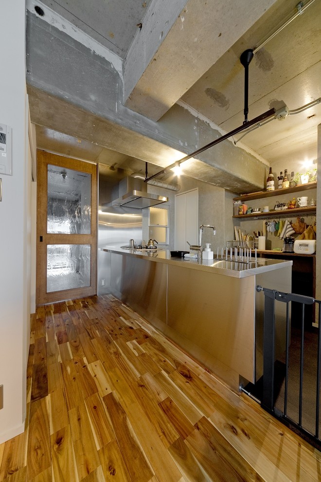 Design ideas for an industrial galley open plan kitchen in Osaka with stainless steel benchtops, medium hardwood floors, with island, beige floor and a single-bowl sink.