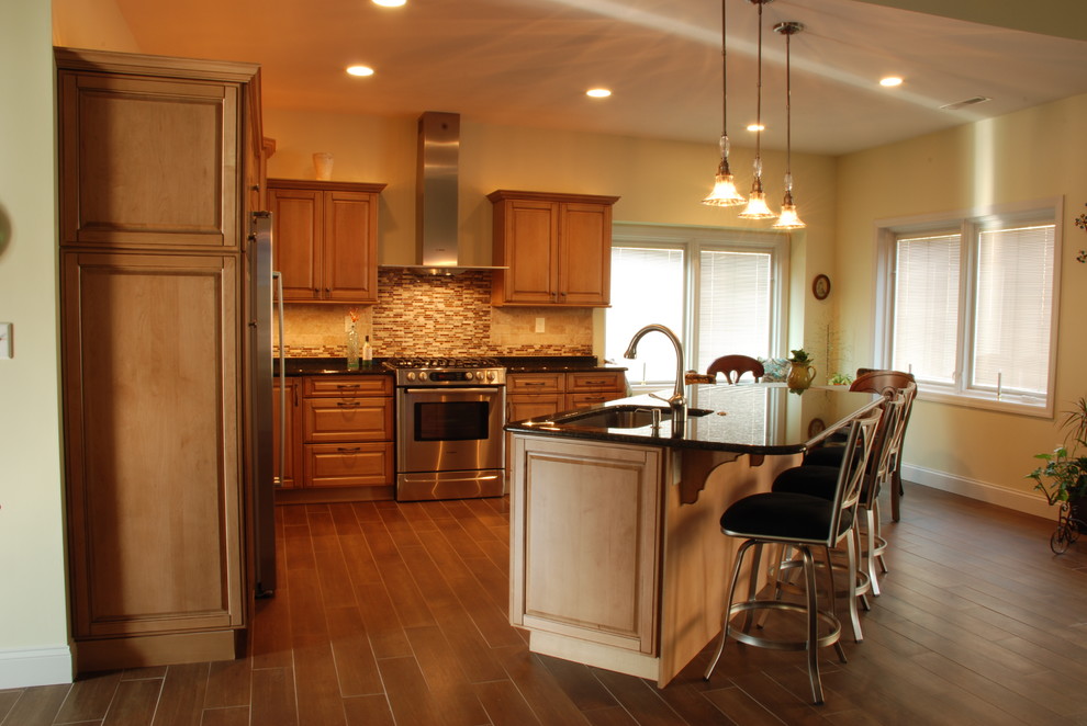 Inspiration for a mid-sized transitional l-shaped ceramic tile eat-in kitchen remodel with a farmhouse sink, raised-panel cabinets, medium tone wood cabinets, granite countertops, beige backsplash, ceramic backsplash, stainless steel appliances and an island