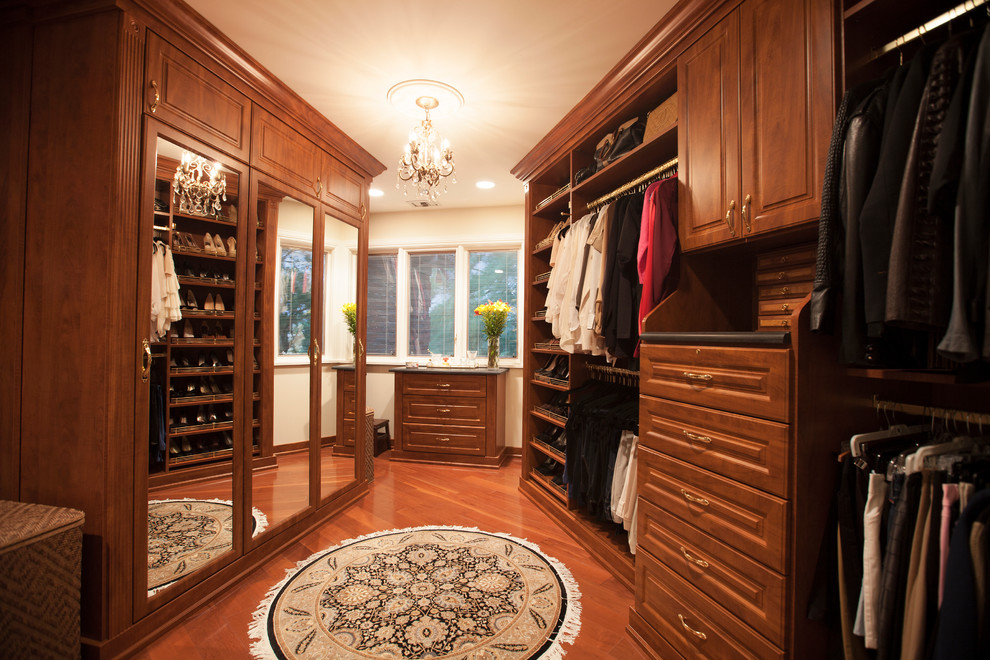 This is an example of a mid-sized traditional gender-neutral walk-in wardrobe in Chicago with raised-panel cabinets, medium wood cabinets, medium hardwood floors and brown floor.