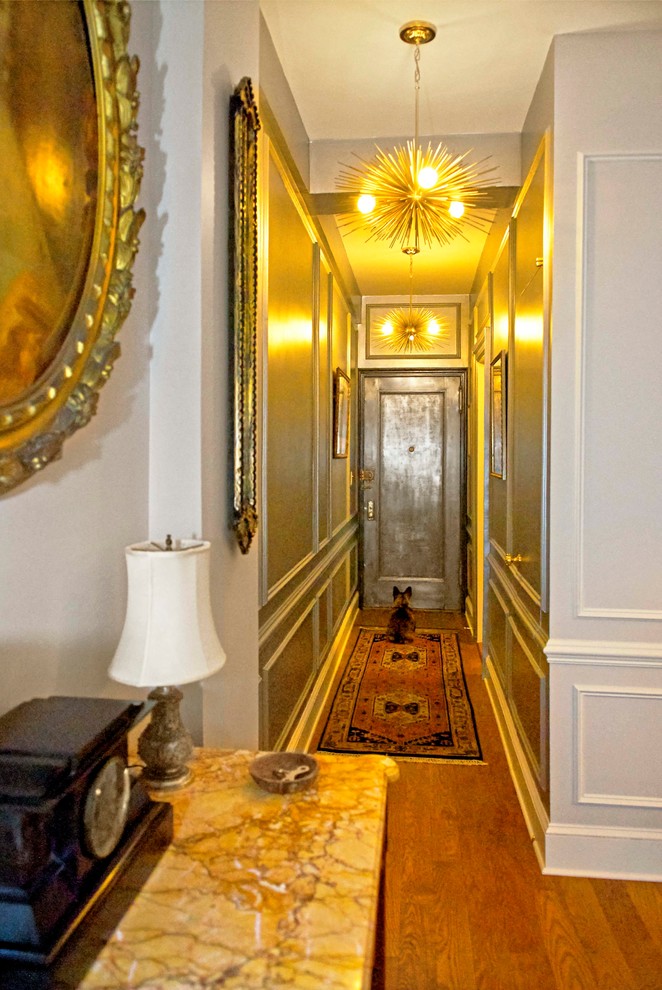 This is an example of a small transitional foyer in New York with metallic walls, medium hardwood floors, a single front door and a metal front door.