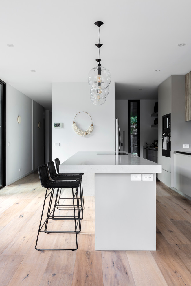 Design ideas for a mid-sized contemporary galley kitchen in Sydney with a single-bowl sink, recessed-panel cabinets, medium wood cabinets, quartz benchtops, metallic splashback, mirror splashback, stainless steel appliances, light hardwood floors and with island.