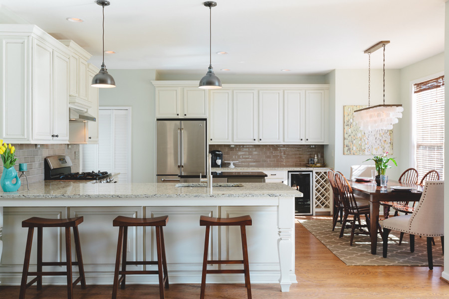 Example of a large transitional u-shaped light wood floor eat-in kitchen design in Atlanta with an undermount sink, raised-panel cabinets, white cabinets, granite countertops, gray backsplash, ceramic backsplash, stainless steel appliances and an island