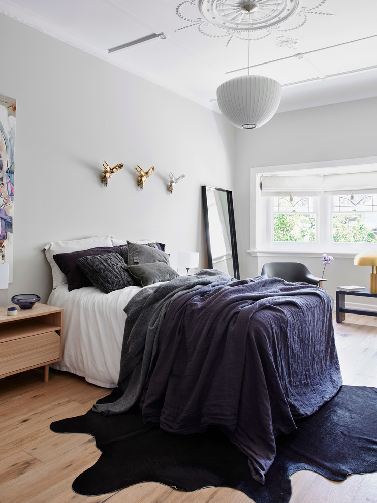 Photo of a scandinavian master bedroom in Melbourne with light hardwood floors.