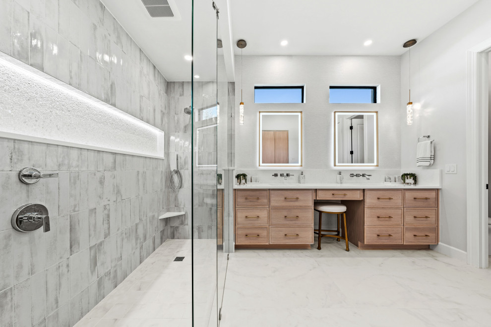 Example of a transitional master gray tile and porcelain tile porcelain tile, white floor and double-sink walk-in shower design with shaker cabinets, light wood cabinets, a two-piece toilet, white walls, an undermount sink, quartz countertops, white countertops, a niche and a built-in vanity