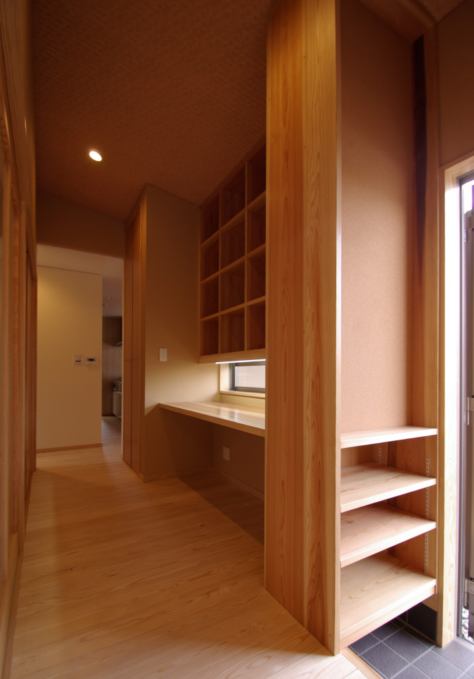 This is an example of a small asian study room in Other with beige walls, light hardwood floors, no fireplace, a tile fireplace surround, a built-in desk, beige floor, timber and wallpaper.