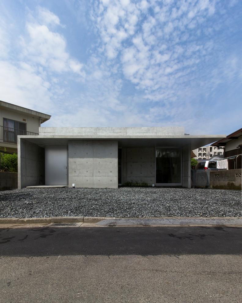 This is an example of a mid-sized modern one-storey concrete grey exterior in Other with a flat roof.