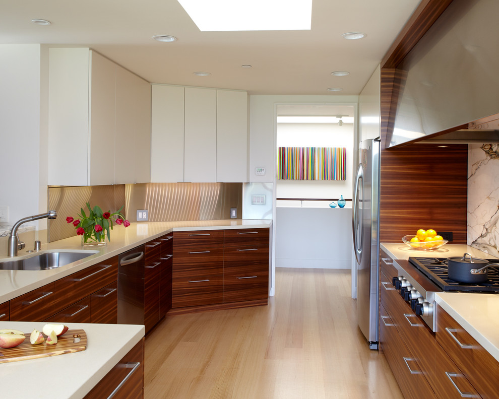 Design ideas for a mid-sized modern u-shaped eat-in kitchen in San Francisco with an undermount sink, flat-panel cabinets, medium wood cabinets, solid surface benchtops, white splashback, stone slab splashback, stainless steel appliances, medium hardwood floors, with island and brown floor.
