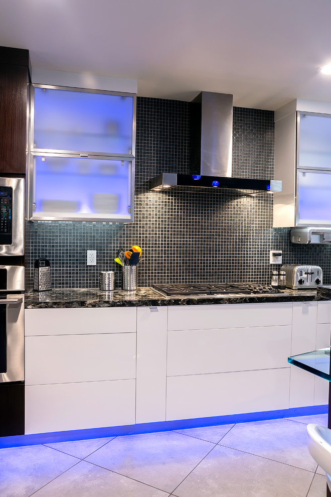 Photo of a mid-sized contemporary u-shaped eat-in kitchen in San Francisco with an undermount sink, flat-panel cabinets, white cabinets, granite benchtops, grey splashback, glass tile splashback, stainless steel appliances, porcelain floors and with island.