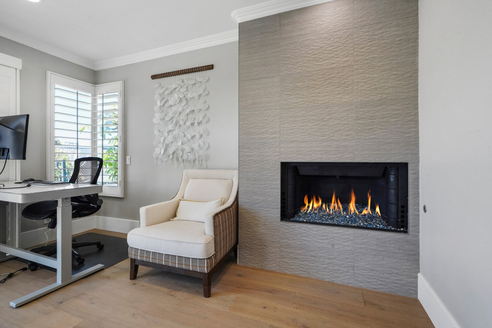 Photo of a large modern home office in Orange County with white walls, a corner fireplace and a tile fireplace surround.