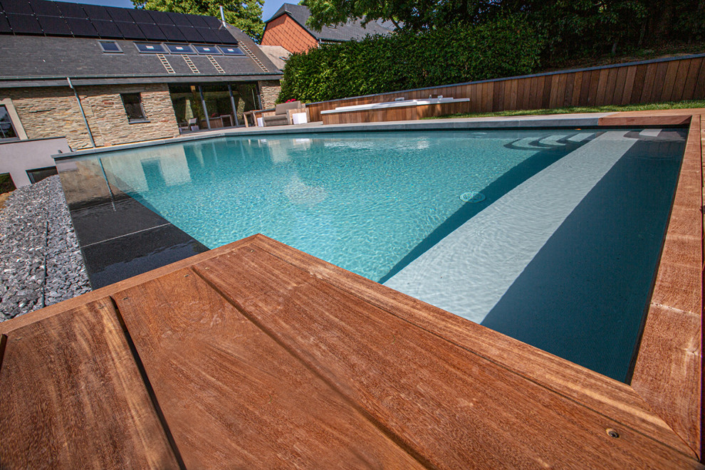 Diseño de piscina infinita moderna grande rectangular con suelo de baldosas