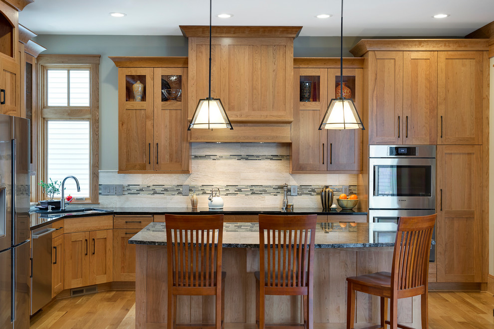 Inspiration for a large transitional l-shaped eat-in kitchen in Minneapolis with an undermount sink, medium wood cabinets, multi-coloured splashback, stainless steel appliances, medium hardwood floors, with island, granite benchtops, recessed-panel cabinets and matchstick tile splashback.