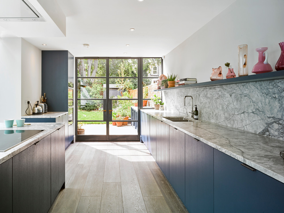 Design ideas for a contemporary kitchen in London with a double-bowl sink, flat-panel cabinets, blue cabinets, granite benchtops, grey splashback, stainless steel appliances, light hardwood floors, with island and beige floor.