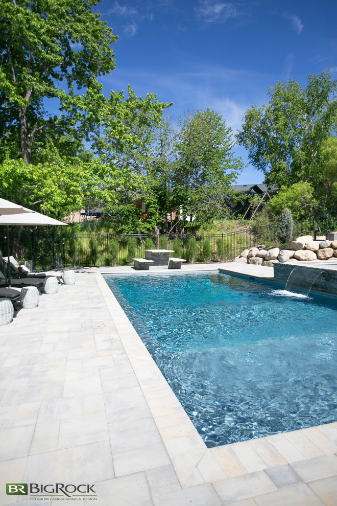 Foto de piscina con fuente actual extra grande rectangular en patio trasero con adoquines de piedra natural
