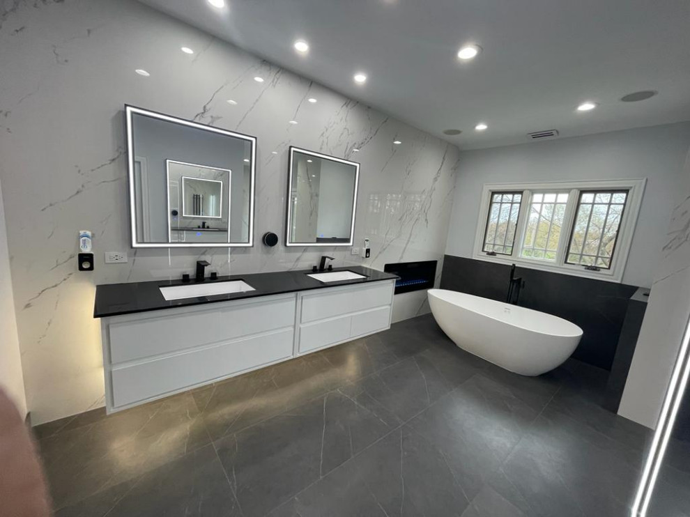Bild på ett stort funkis svart svart en-suite badrum, med släta luckor, vita skåp, ett fristående badkar, en kantlös dusch, en bidé, vit kakel, porslinskakel, vita väggar, klinkergolv i porslin, ett nedsänkt handfat, bänkskiva i kvartsit, grått golv och med dusch som är öppen