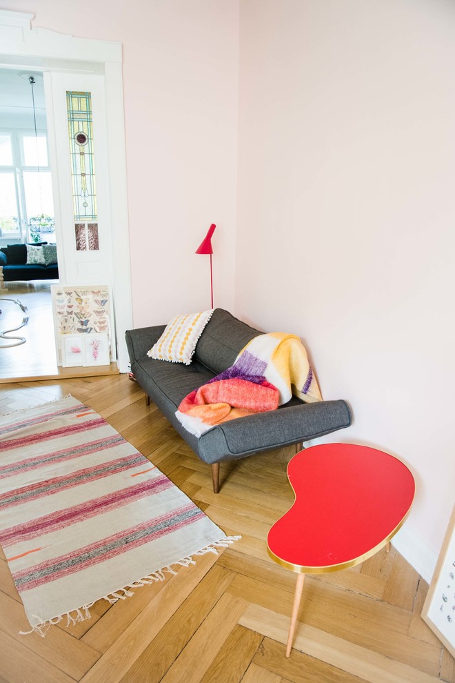 This is an example of a small eclectic living room in Berlin with pink walls and medium hardwood floors.