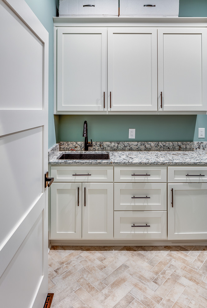 Photo of a mid-sized country single-wall dedicated laundry room in Other with an undermount sink, shaker cabinets, white cabinets, blue walls, beige floor and multi-coloured benchtop.