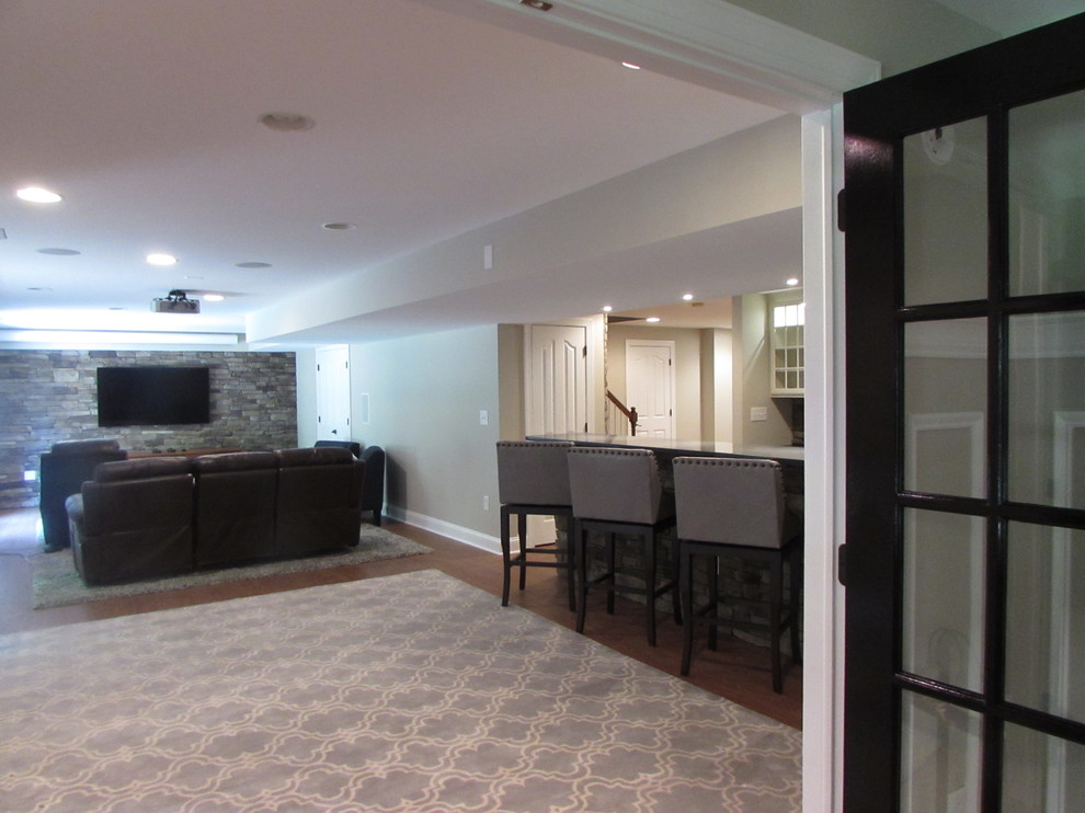 Inspiration for a large walk-out vinyl floor basement remodel with beige walls, a standard fireplace and a stone fireplace