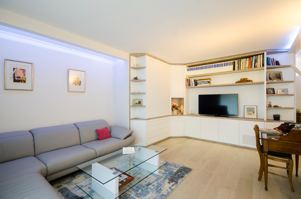 This is an example of a large contemporary enclosed family room in Paris with a library, white walls, light hardwood floors, no fireplace and a freestanding tv.